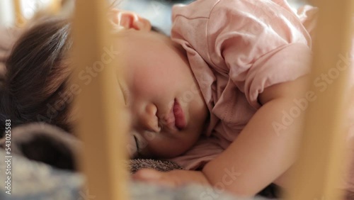 Asian baby girl napping in her crib peacefully. Tight dolly shot.