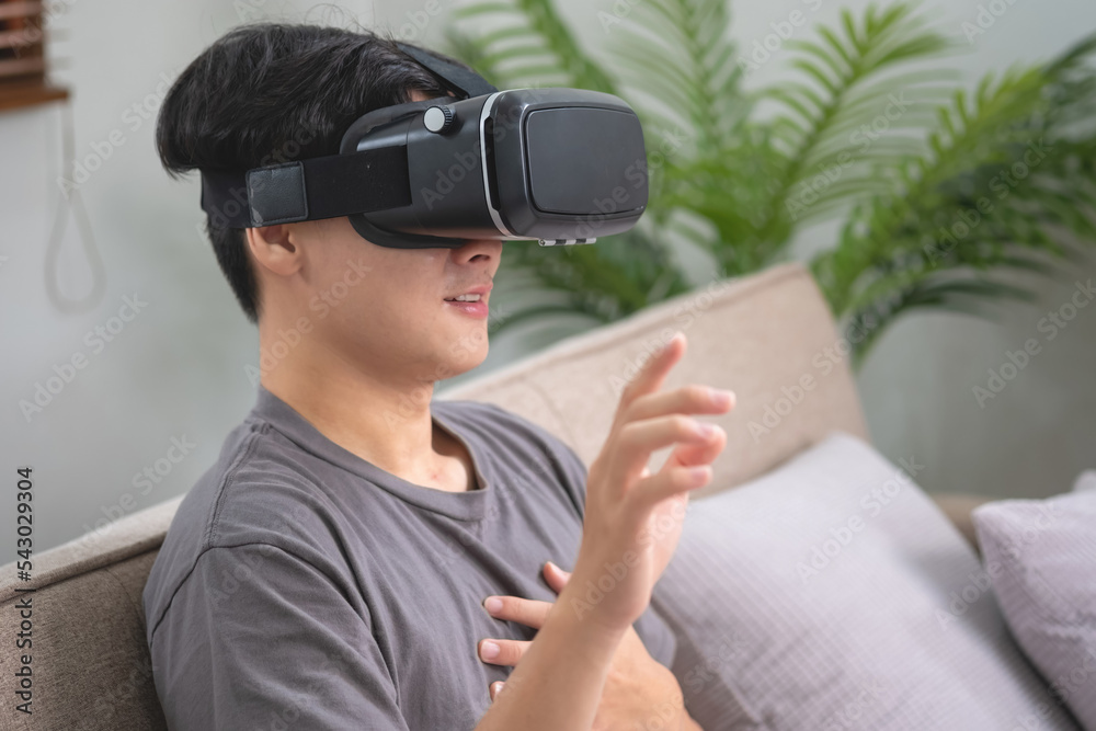 relieve stress on vacation Happy Asian man relaxing at home playing VR virtual reality game on vacation. relieve stress on vacation Happy Asian man relaxing at home playing VR virtual reality game on vacation.