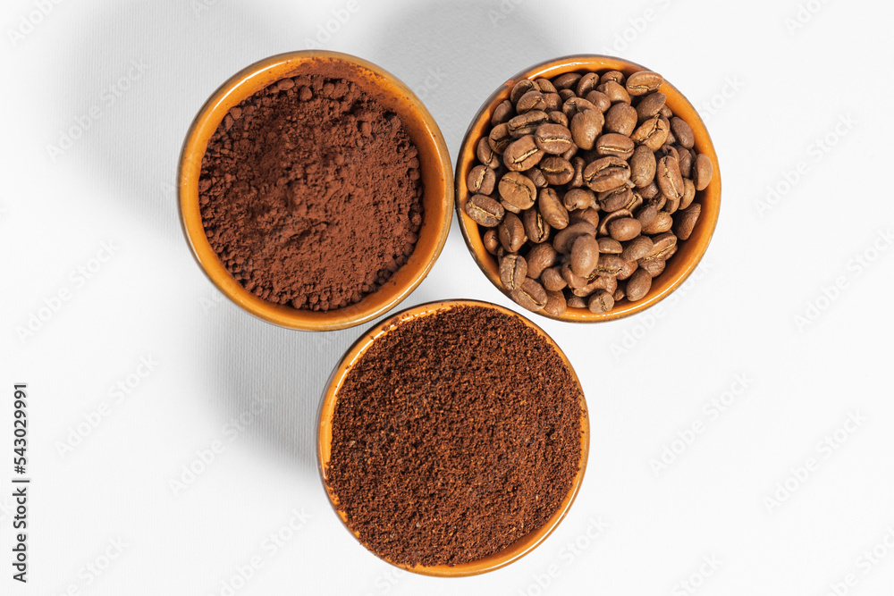 Cups with roasted coffee beans and ground coffee, white background and copy space. Cups with roasted coffee beans and ground coffee, white background and copy space.