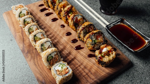 Closeup of a set of delicious fresh sushi rolls, chopsticks, and soy sauce on a  wooden board