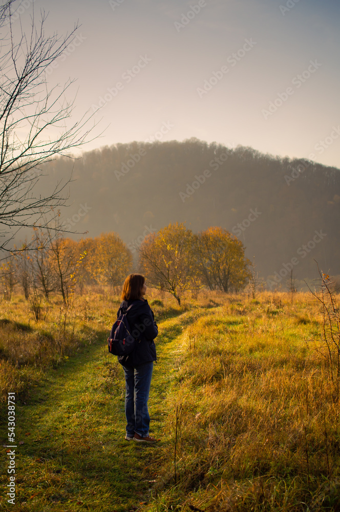 The girl looks into the distance in the bosom of nature on an autumn bright sunny day