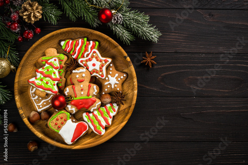 Christmas gingerbread in the plate with spices and decorations on dark wooden table. Christmas baking. Top view with copy space.
