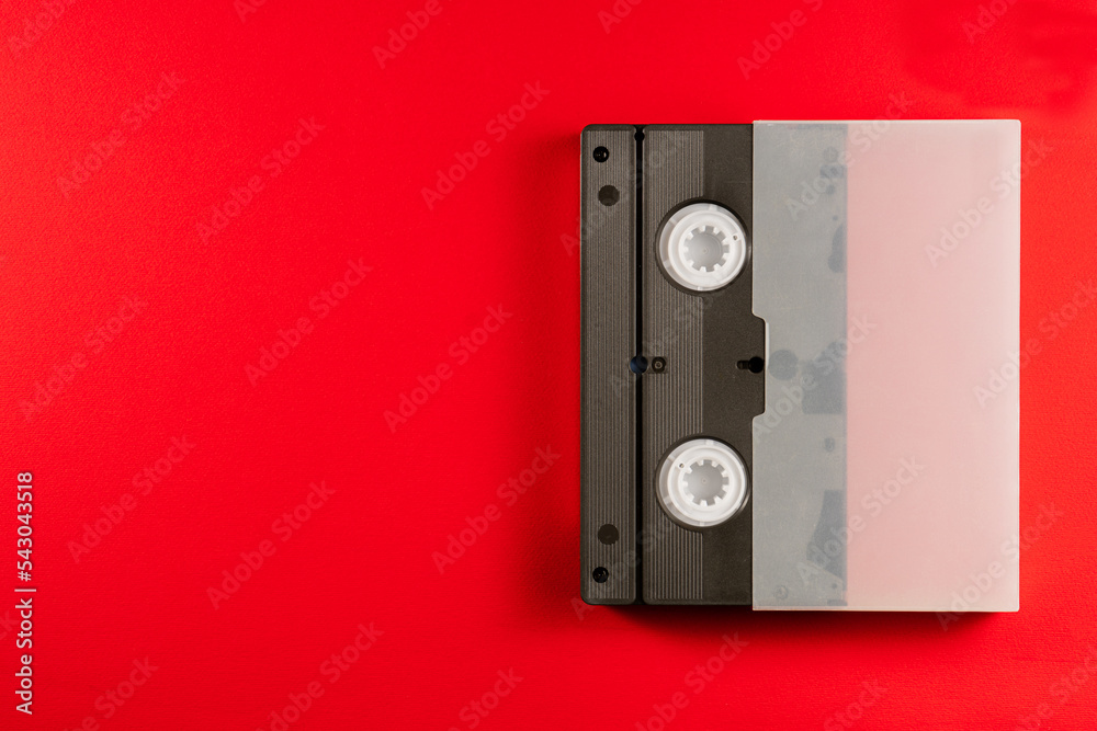 Black vintage VHS videotape cassette in a white case on red background
