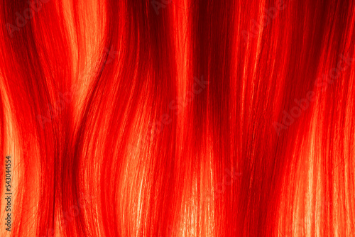 Texture of blonde combed hair illuminated by red light. Strands of light woman hair. Curl of healthy natural female hair. Synthetic wig. Macro shot of long straight locks of hair.
