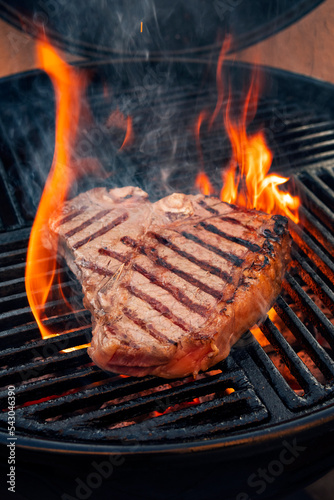 Barbecues dry aged Wagyu Porterhouse Steak vom Rind gegrillt als close-up auf einem Holzkohle Grill mit Feuer und Rauch