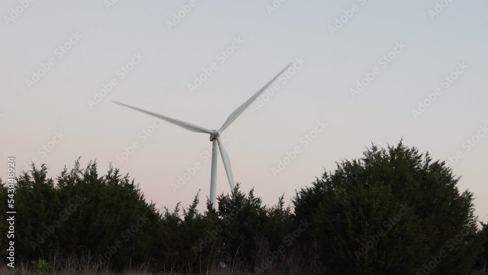 Wind farm windmill with large blades against the background of the evening sky in forest on hills. Wind farm windmill with large blades against the background of the evening sky in forest on hills.