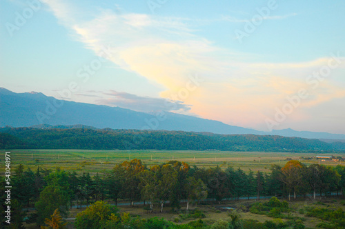 Beautiful landscape of mountains and trees at sunset. Bird's-eye view of derya - cypresses, eucalyptus trees. Mountains covered with trees rise on the horizon. Sunset over Pitsunda. photo