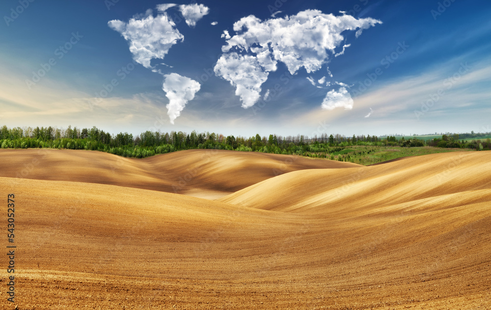 Fototapeta premium clouds in the form of a map of the world over the field. Travel and landscape concept. hilly field