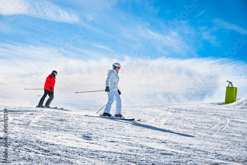 Couple, man and woman skiing down the ski slope or piste in Pyrenees Mountains. Winter ski holidays in El Tarter, Grandvalira, Andorra photo