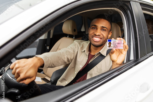  Happy young african man showing his driver's license from open car window