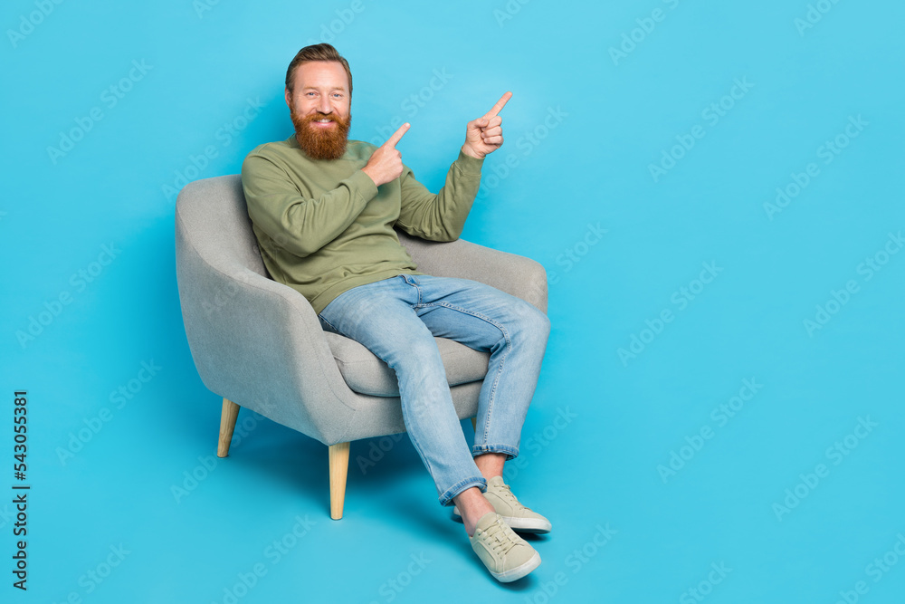 Portrait of handsome optimistic man with red hairstyle wear khaki pullover directing empty space isolated on blue color background Portrait of handsome optimistic man with red hairstyle wear khaki pullover directing empty space isolated on blue color background