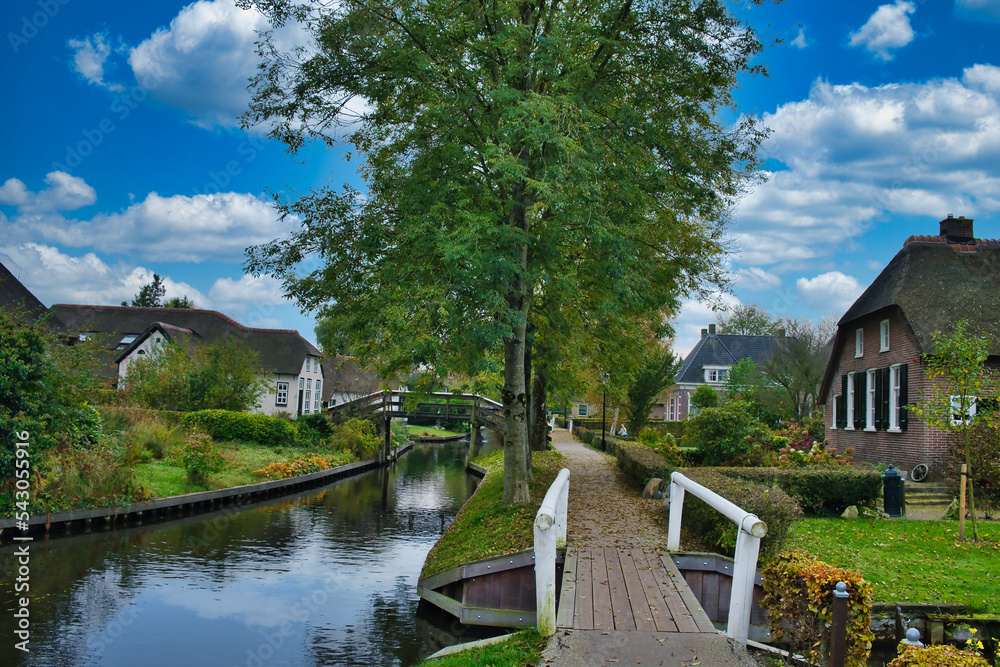 Φωτογραφία The picturesque Dutch village of Giethoorn, with a canal, narrow wooden bridges, trees and thatched old farmhouses