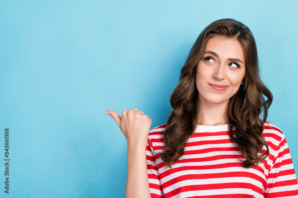 Photo of pretty cute cunning lady wear stylish outfit interested look thumb direct empty space news isolated on blue color background Photo of pretty cute cunning lady wear stylish outfit interested look thumb direct empty space news isolated on blue color background