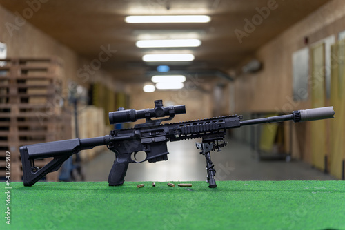Foto A rifle with an optical sight and a silencer in a shooting range.