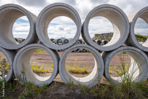 Concrete Shackles piled up in a factory, on a construction site. Basic sanitation works to supply water and sewage to the population. Cement shackles pilled on a lawn.