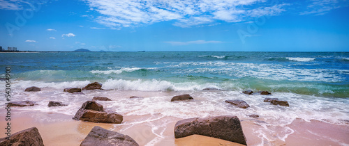 A windy day at the beach at Alexandra Headland, Maroochydore, Sunshine Coast, Australia. Waves crash onto rocks.