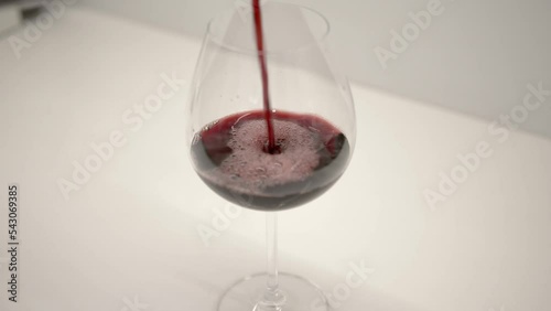 Red wine pouring into wine glass on a white background kitchen, evening lifestyle calm vibe. photo