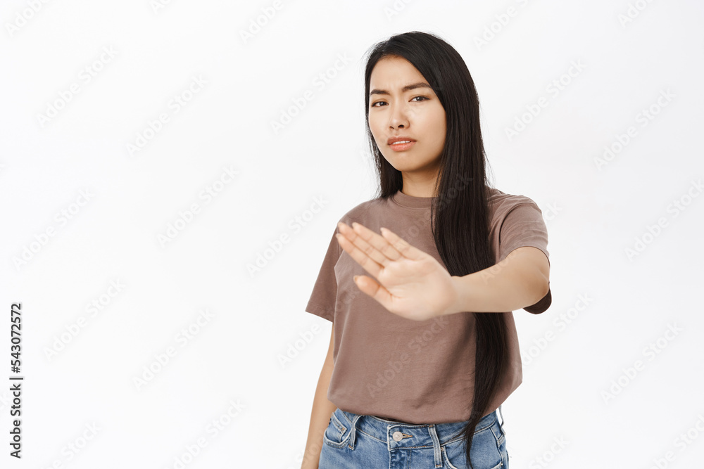 Stop, stay back. Concerned asian woman extends her hand to prohibit, reject smth, forbid action, decline smth bad, stands over white background Stop, stay back. Concerned asian woman extends her hand to prohibit, reject smth, forbid action, decline smth bad, stands over white background