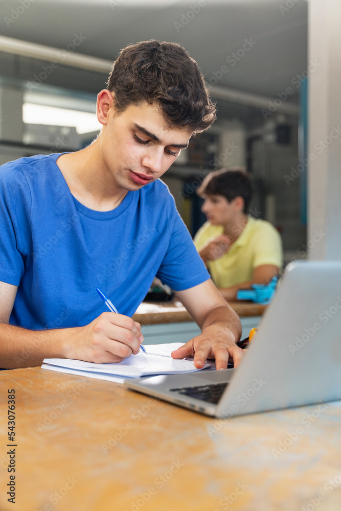 Young boy student writing exercise in the college technology classroom Young boy student writing exercise in the college technology classroom