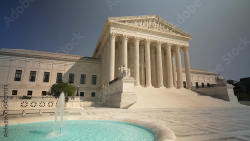 Facade of US Supreme Court building with Authority of Justice sculpture in front in Washington DC on a sunny summer evening.
