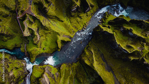 birdview of Fjadrargljufur canyon with a river meandering through the middle of the canyon with waves and water splash