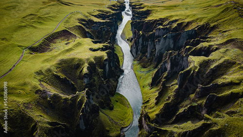 birdview of Fjadrargljufur canyon with a river meandering through the middle of the canyon and a trail on the side