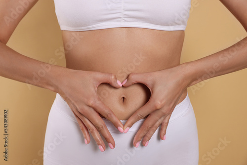 Wallpaper Mural Woman in underwear making heart with hands on her belly against beige background, closeup. Healthy stomach Torontodigital.ca