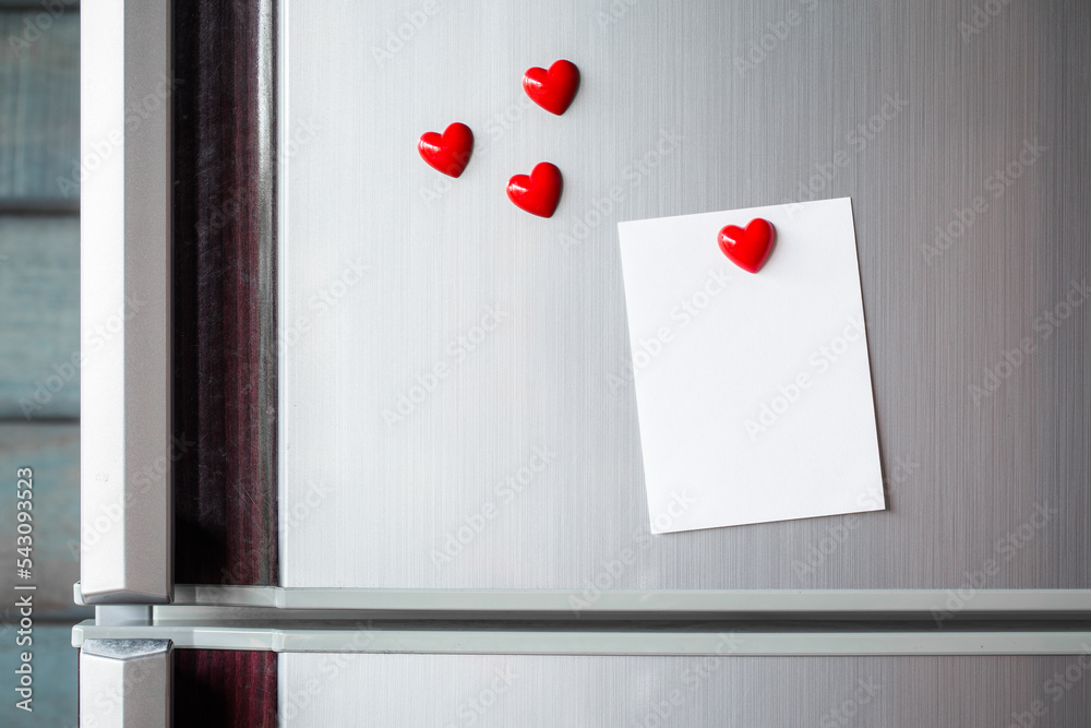 Empty paper sheet on refrigerator door. Note paper with magnetic heart. Valentine send text love message.
