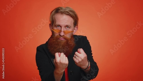 Greedy avaricious young man showing fig negative gesture, you dont get it anyway. Rapacious, avaricious, acquisitive. Body language. Refusal fig sign. Young guy isolated on orange studio background