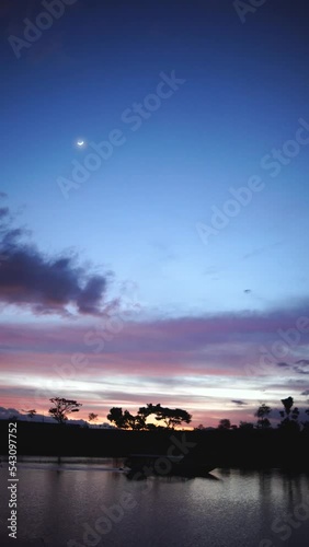 vertical view the footage dramatic sunset at lake then boat passing the river with rich color of sky and moon shine