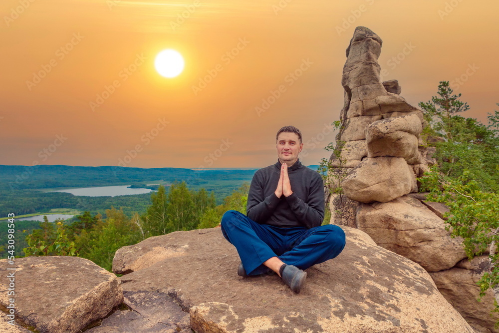 young handsome man on a rock on the Arakul shihan enjoys on a summer day