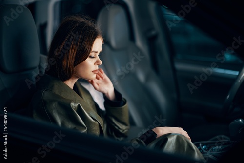 a sweet, relaxed, stylish woman is sitting in a black car at night and enjoying the ride