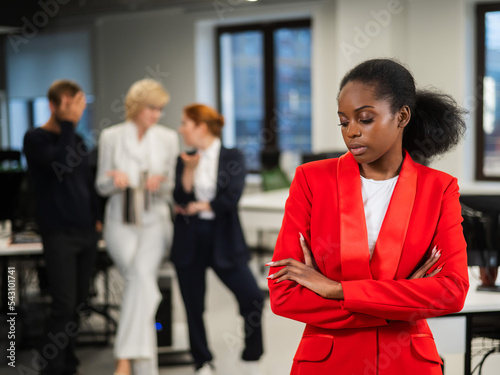 Young african woman is upset because of the ridicule of colleagues. Racial discrimination in the office. 