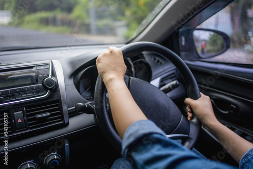 Female hands on the steering wheel of a car while driving. Close-up of a woman's hand driving a car