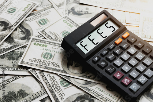 Calculator with the word FEES on the calculator placed on the dollar, concepts, fees, fees services and taxes. photo