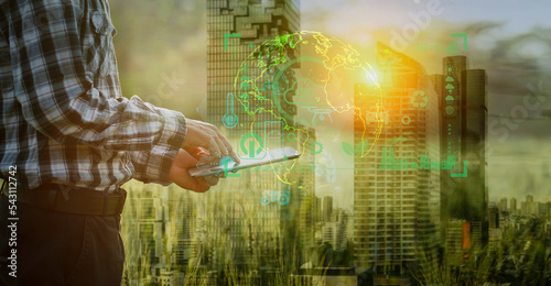 Double exposure business hands using digital tablet with Energy of natural green house, Sustainable and network connection icons on green cityscape.