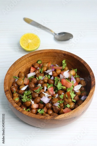 High in protine boiled black chana or chickpea salad. Chopped tomatoes, onion, chilies, and coriander mixed with boiled chickpea or Bengal gram. Weight loss meal. Served with Lemon. Copy space. photo