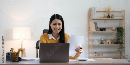 Portrait of Young Asian woman hand freelancer is working her job on computer tablet in modern home. Doing accounting analysis report real estate investment data, Financial and tax systems concept.