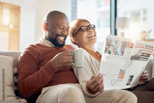 Happy, smile and couple reading a newspaper while relaxing on a sofa in the living room of their home. Happiness, love and mature interracial people laughing, resting and bonding together at a house.