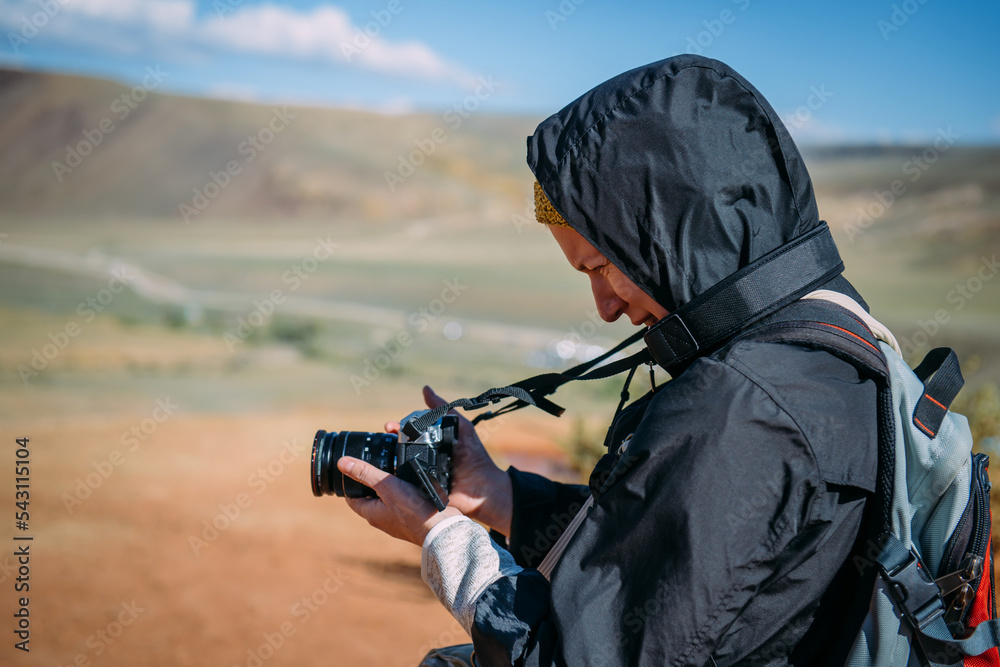 Woman photographer taking pictures of beautiful landscape. Close up female tourist holding camera on mountain background.
