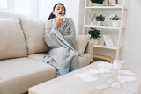 Woman cold headache runny nose and stuffy nose sitting on sofa in plaid, treatment for flu, allergies and covid-19