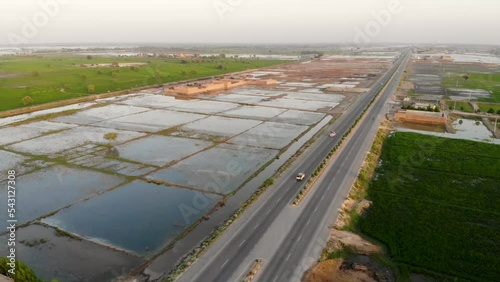 Aerial View Of Highway Cutting Through Rural Jacobabad With Water Logged Fields On Left Hand Side. Dolly Forward  photo