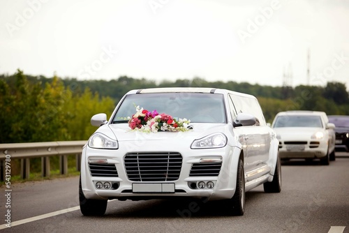 Wedding cars decorated with fresh flowers go on the road column.