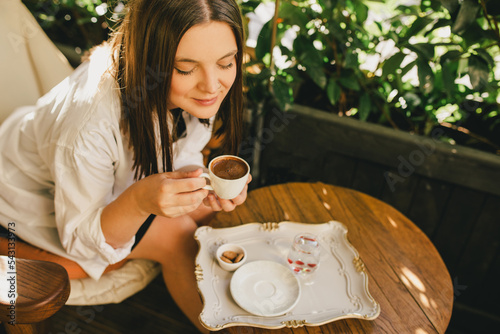 Foto Woman enjoying traditional Turkish coffee sitting by wooden table