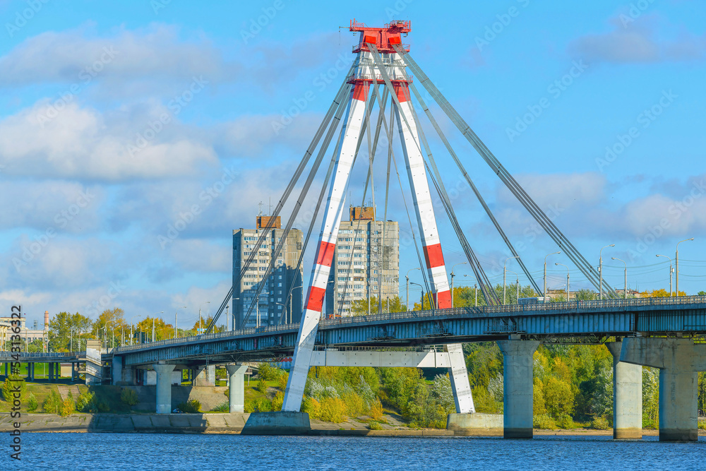 Obraz premium A fragment of a cable-stayed bridge in selective focus across the bed of the Sheksna River with the city of Cherepovets in the background.