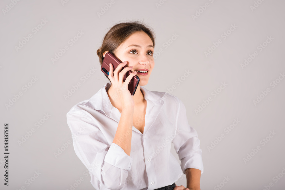 A businesswoman is talking on a mobile phone on a gray background. A businesswoman is talking on a mobile phone on a gray background.