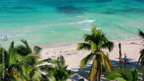 aerial of two girls walking to shoreline on beautiful white sand beach with turquoise water at Xpu Ha in Mexico on sunny summer day photo