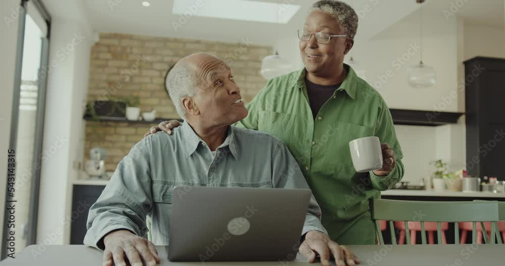 Senior Adult Couple Using Laptop in Kitchen Senior Adult Couple Using Laptop in Kitchen