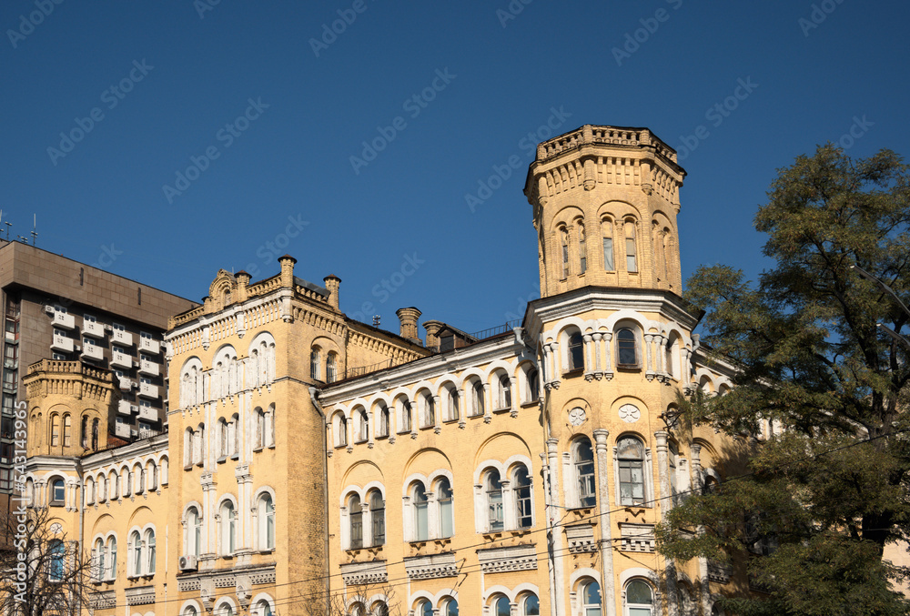 Panoramic landscape view of vintage yellow brick building with the tower against blue sky in downtown of Kyiv. Neo-gothic style architecture. Kyiv, Ukraine