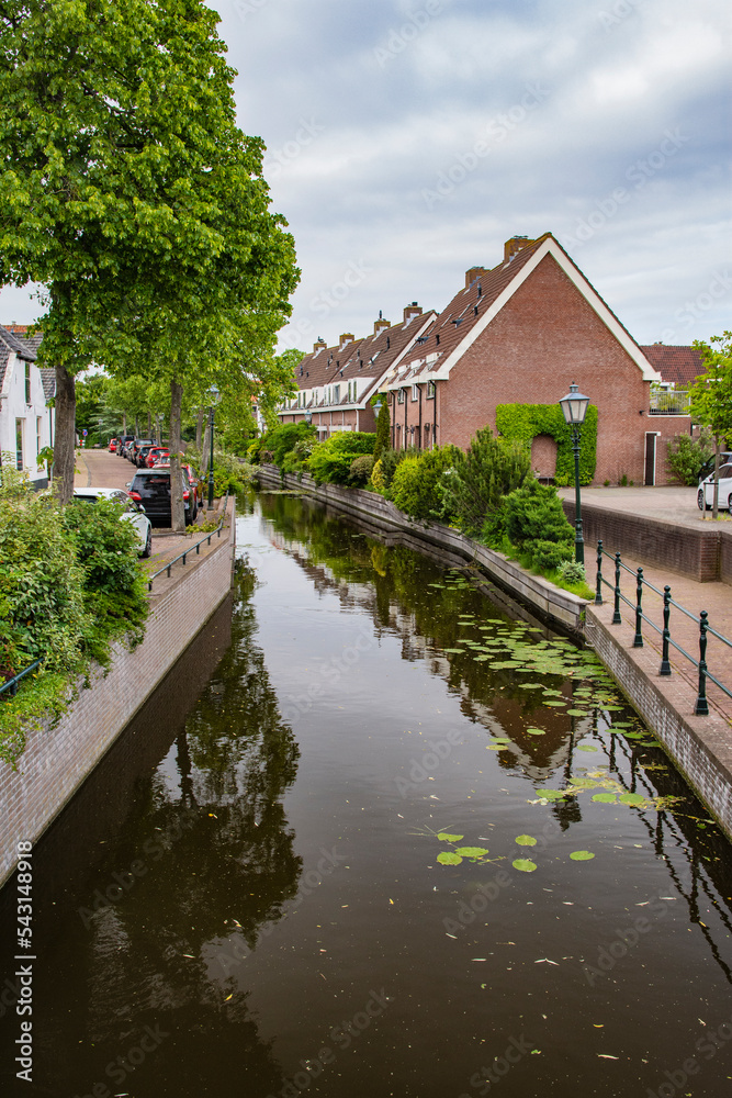 Fototapeta premium Road and brick houses by a canal in the Netherlands. Summer.